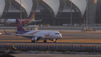 Bangkok, thailand - januari 19, 2023. flygplan flygbuss a320, hs-txj av thai leende taxning på de flygfält modern suvarnabhumi flygplats, bangkok. rad av plan dockad till de terminal. video