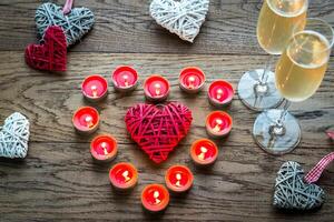 Two glasses of champagne with burning candles and cane hearts photo