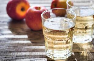 Two glasses of cider on the wooden background photo