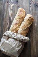 Two baguettes on the wooden background photo