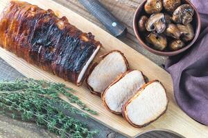 Pork loin wrapped in bacon with roasted mushrooms photo