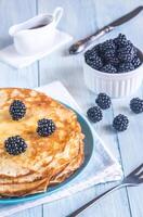 Crepes with blackberries on the wooden table photo