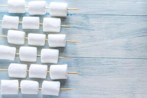 Marshmallow skewers on the wooden background photo