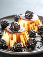 Vanilla puddings with fresh blackberries and berry topping photo