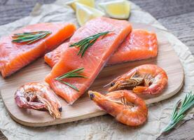 Raw salmon with shrimps on the wooden board photo