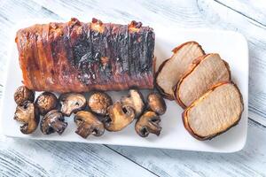 Pork loin wrapped in bacon with roasted mushrooms photo