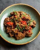 AI generated Rendang with sliced chilies on a light green plate on a gray table background photo