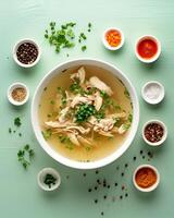 AI generated Chicken soup in a white bowl with small bowls of ingredients around it on a light green top table photo