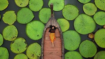 aéreo ver de un asiático mujer relajante en un barco al aire libre en loto estanque a phuket Tailandia foto