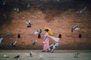 Asian girl and Flying pigeons near Tha Phae gate at Old city in Chiang Mai Thailand photo