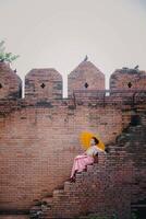 niña en frente de histórico eso fae portón a antiguo ciudad en chiang mai Tailandia foto