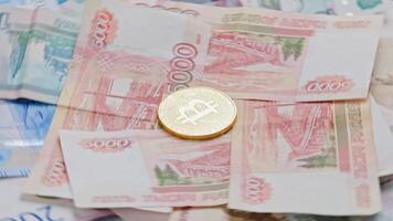 Looped rotation of golden bitcoin shiner on Russian rubles paper banknotes video