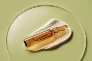 Ampoule in a drop of cosmetic cream on a green background. photo