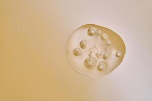 A drop of serum with bubbles on a beige nude background. photo