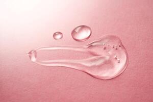 A drop of transparent cosmetic gel on a pink background. photo