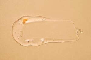 A drop of transparent cosmetic gel on a beige background. photo