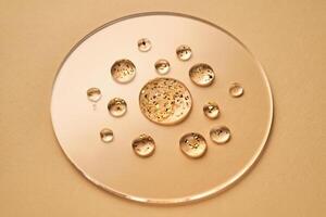 suero con 24k oro partículas gotas en un beige antecedentes. foto