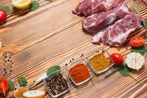 Raw pork meat with spices and vegetables on wooden table. photo