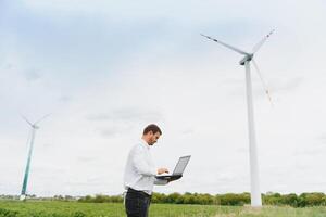 ingeniero trabajador con ordenador portátil o computadora a viento turbina poder estación construcción sitio, copiar espacio. foto