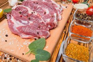 Raw pork meat with spices and vegetables on wooden table. photo