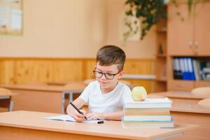 pequeño niño escritura con vistoso lápices, adentro. elemental colegio y educación. niño aprendizaje escritura letras y números. foto