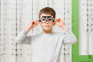 Boy with trial frame. Kid patient to check vision in ophthalmological clinic photo