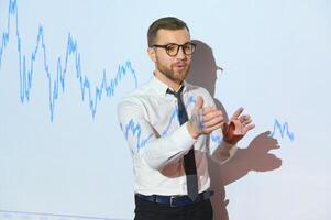 Man is standing near projector and showing graphs and business graphs. photo