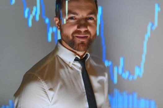 Stock Market Top Trader Looks at Projected Ticker Numbers and Graphs Running, Analysing Data to Make Best Sell. Behind Him Room Full of Screens and Statistics. photo