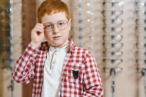 Handsome boy choosing glasses at optics store. health care and vision concept photo