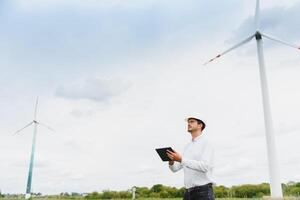 Wind turbines generating electricity. energy conservation concept and worker staff engineer hold tablet photo