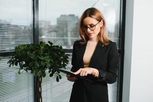 Portrait of middle age businesswoman standing with digital tablet at office. Business people. photo