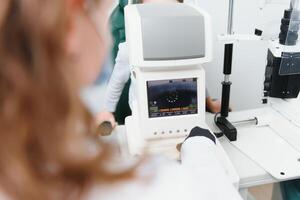 Modern medical equipment. Close up of ophthalmologist using auto refractometer while examining child eyes. photo