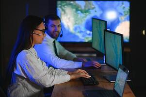 Center of dispatching maintenance. Portrait of cheerful woman and man working via headset microphone while sitting on navigation controller board photo