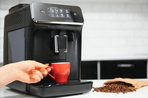 Modern espresso coffee machine with a cup in interior of kitchen closeup photo