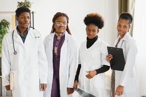 female doctor holding a stethoscope with her team behind. photo