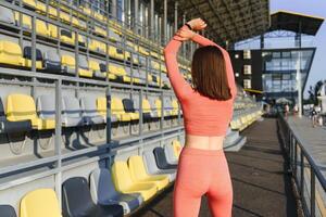 deporte y bienestar. aptitud niña haciendo extensión ejercicio. Moda deportivo mujer con fuerte muscular cuerpo capacitación. ajuste hembra extensión a al aire libre estadio foto