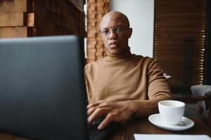 Close up portrait of young man sitting in cafe working on laptop computer. photo