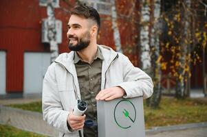 Man holding electric car charger at charging station photo