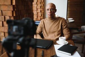 African-Ameican entrepreneur wearing shirt with rolled up sleeves looking through window with thoughtful and serious face expression, feeling nervous before meeting with business partners at cafe. photo