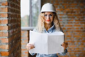 hermoso mujer ingeniero es revisando el planes de un construcción trabajo foto