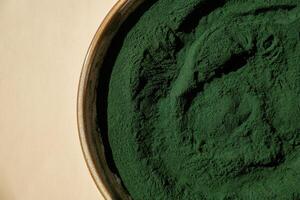 Natural organic green spirulina algae powder in bowl on neutral background. Chlorella seaweed vegan superfood supplement source and detox. Copy space Healthy nutritional antioxidant concept photo