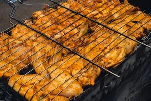 BBQ picnic time Roasted chicken legs and wings on grill. Grilling meat on outdoor grill grid tasty barbeque chicken steak with smoke flames juicy meat in the backyard in summer photo