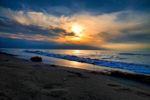 Sunset, illuminated sea. Sandy beach in the foreground. Light waves. Baltic Sea photo