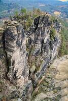 Jagged rocks at the Basteibridge. Wide view over trees and mountains. National park photo