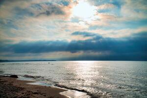 Sunset, illuminated sea. Sandy beach in the foreground. Light waves. Baltic Sea photo