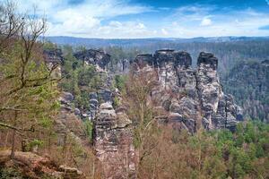 Jagged rocks at the Basteibridge. Wide view over trees and mountains. Dramatic sky photo