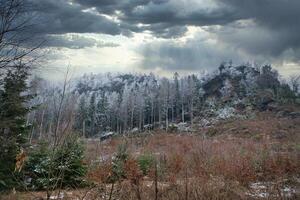 Zschirnstein with snow-covered trees and dramatic clouds with rays of sunshine. photo