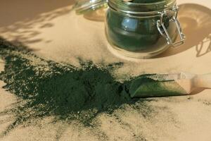 Organic blue-green algae spirulina powder food in glass jar with wooden spoon. Health benefits of spirulina chlorella. Dietary supplement superfood concept photo