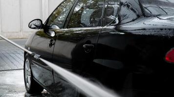 Lavado lujo negro coche en sin contacto coche lavar. limpieza el detalles de coche. Lavado sedán coche con espuma autoservicio y alto presión agua. limpieza y orden en urbano ambiente foto
