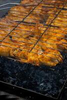 Delicious chicken frying on barbecue grill grate outdoor. Seasoning falling on fresh grilled chicken wings. Summer party food ideas. BBQ Juicy roasting chicken grill legs on grill grate photo